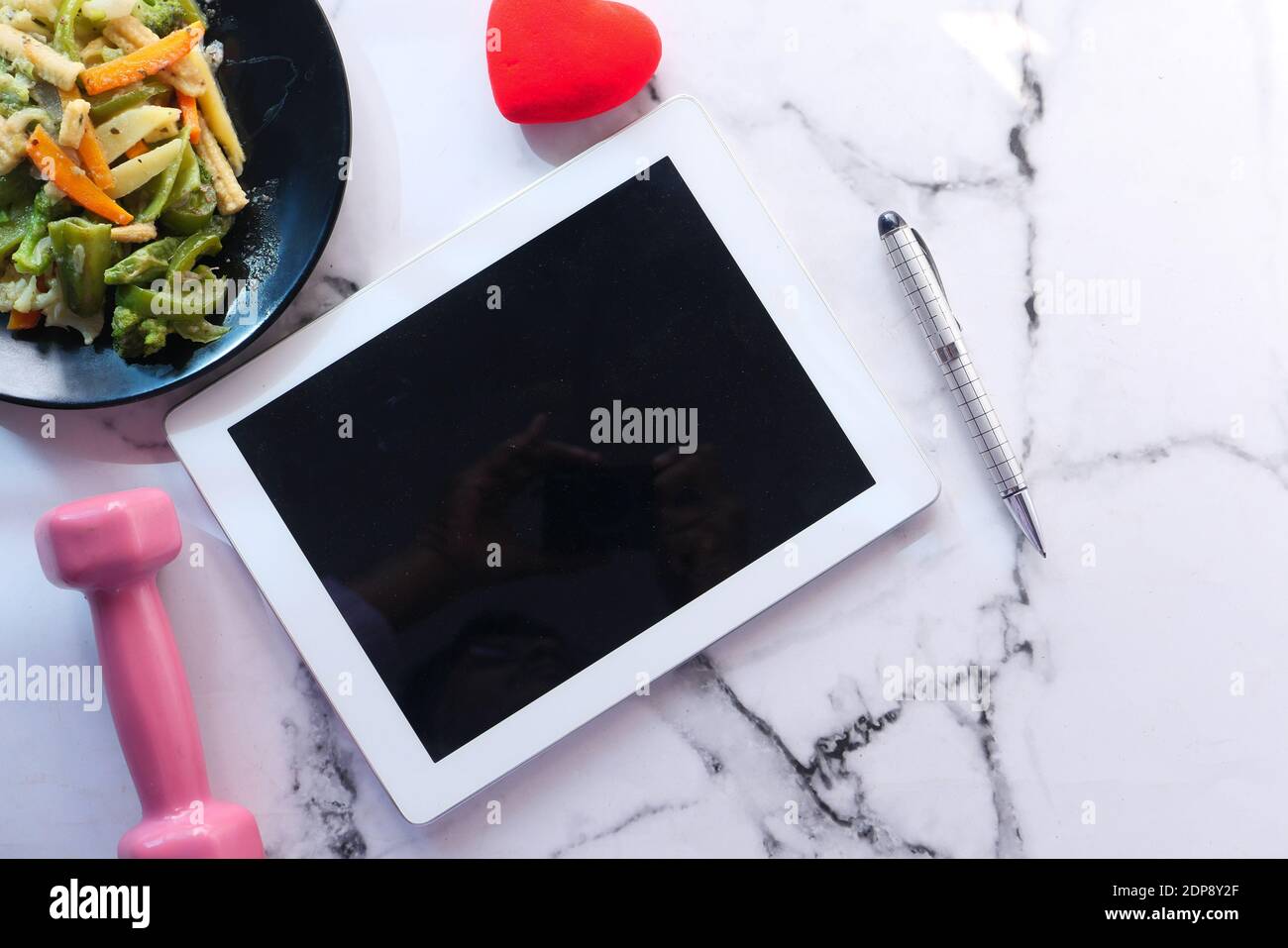 Digitale Tablette, Hantel und Salat auf dem Teller Stockfoto