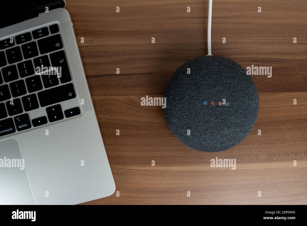 London, Vereinigtes Königreich - 19. Dezember 2020: Charcoal Google Nest Home Mini Smart Speaker mit eingebautem Google Assistant neben einem Laptop auf einem Schreibtisch. Stockfoto