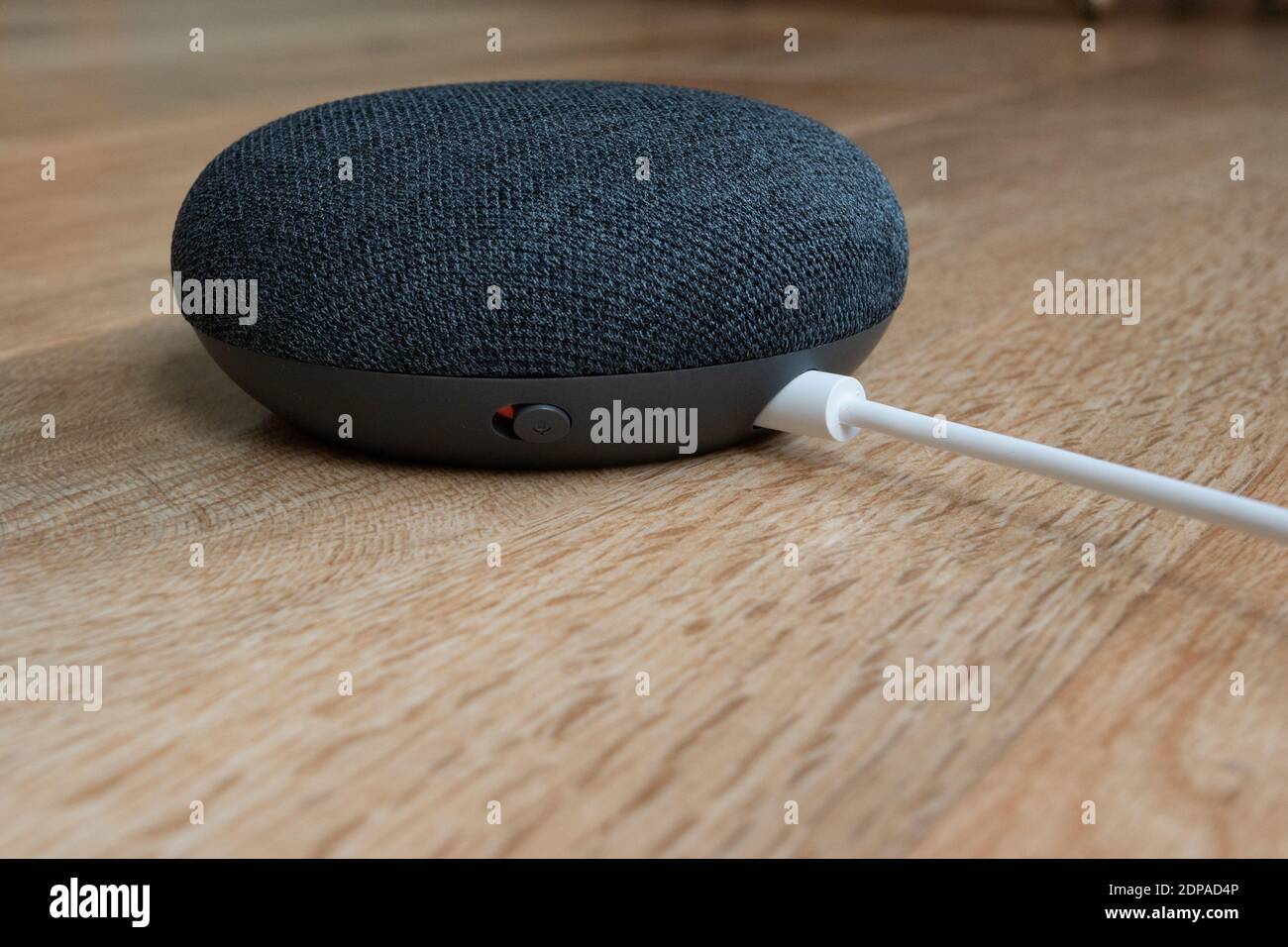 London, Vereinigtes Königreich - 19. Dezember 2020: Charcoal Google Nest Home Mini Smart Speaker mit eingebautem Google Assistant auf einem Holztisch. Stockfoto