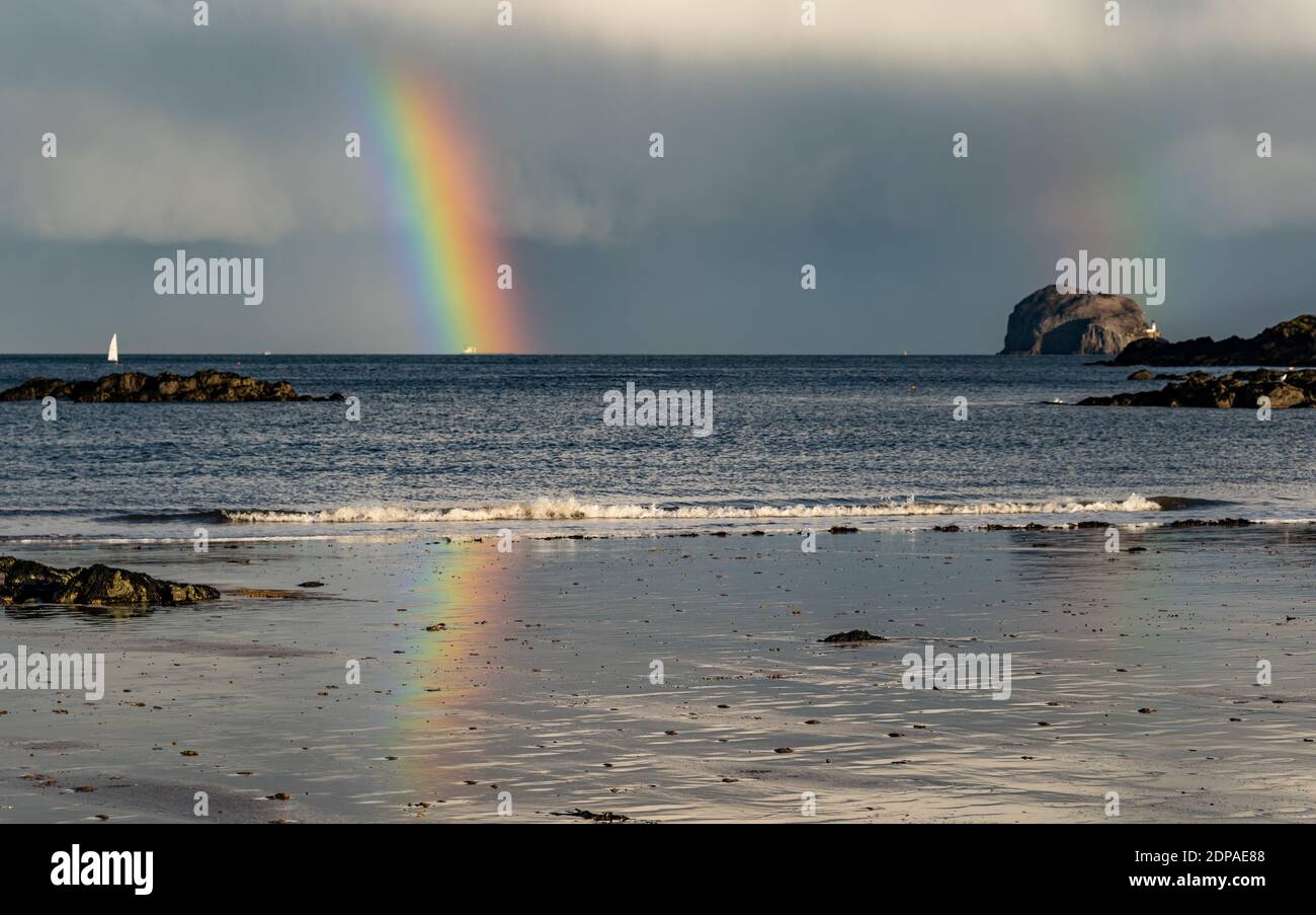 North Berwick, East Lothian, Schottland, Großbritannien, 19. Dezember 2020. UK Wetter: Ein doppelter Regenbogen erscheint nach Regen, der den Firth of Forth und den Bass Rock aufschlägt und sich im nassen Sand am Strand widerspiegelt Stockfoto