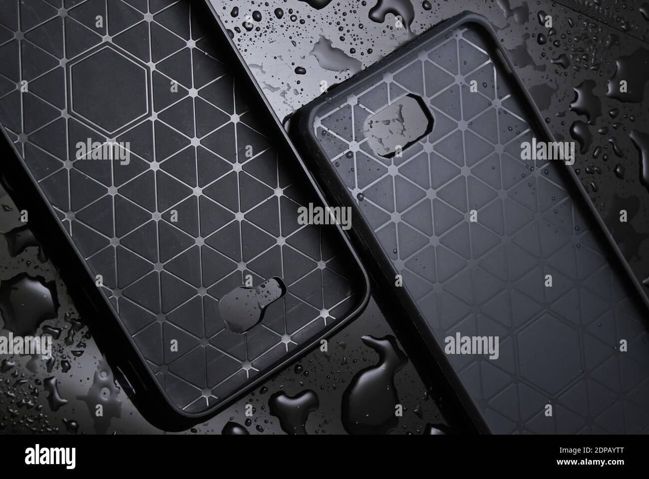Schützende Smartphone-Hüllen auf schwarzem Hintergrund mit Wassertropfen. Schützen Sie Ihr Smartphone vor Wasser Stockfoto