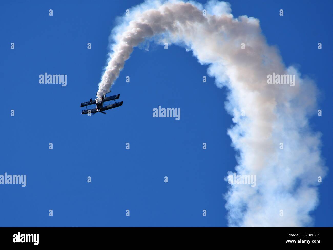 Pitts Modell 12 Stunt-Doppeldecker mit Rauchspur und blauem Himmel. Stockfoto