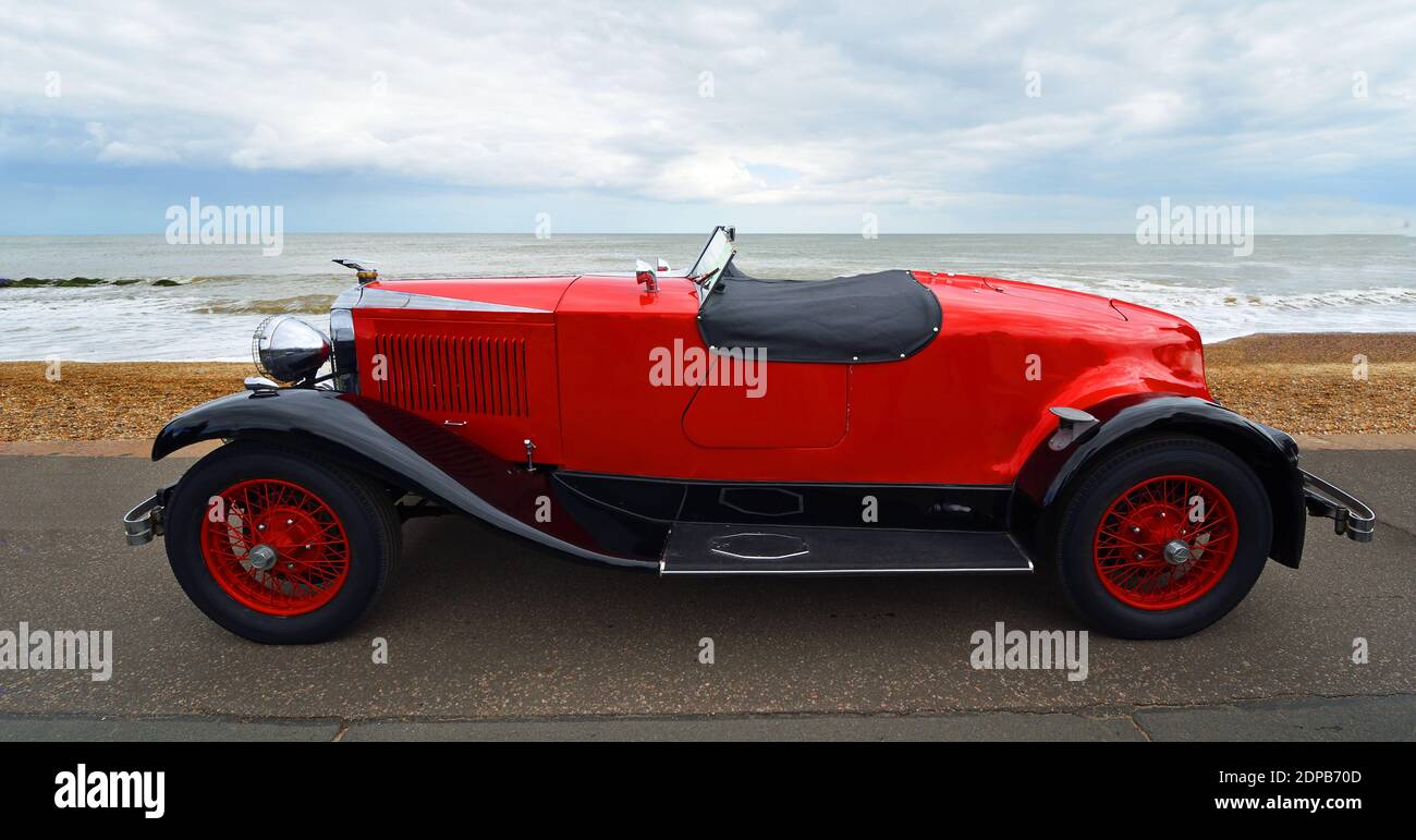 Classic Red Vauxhall Motor Car an der Strandpromenade mit Strand und Meer im Hintergrund geparkt. Stockfoto