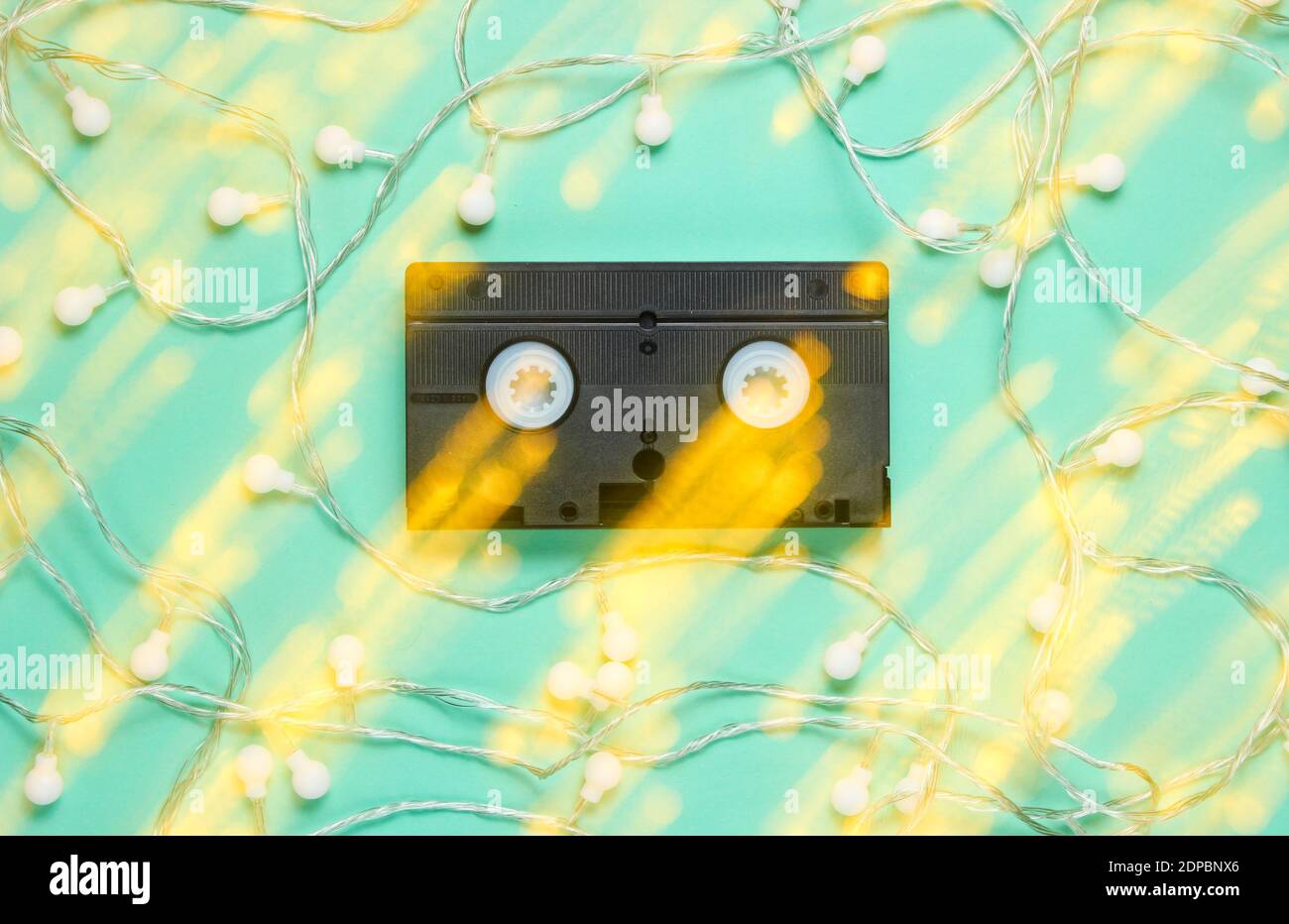 Retro vhs Videoband mit leuchtend leuchtenden LED Girlanden auf blauem Hintergrund. Lichteffekt Draufsicht, Minimalismus Stockfoto