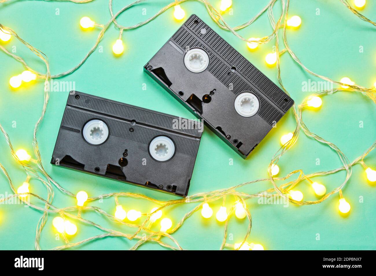 Retro vhs Videoband mit leuchtend leuchtenden LED Girlanden auf blauem Hintergrund. Aussicht von oben, minimalistisch Stockfoto