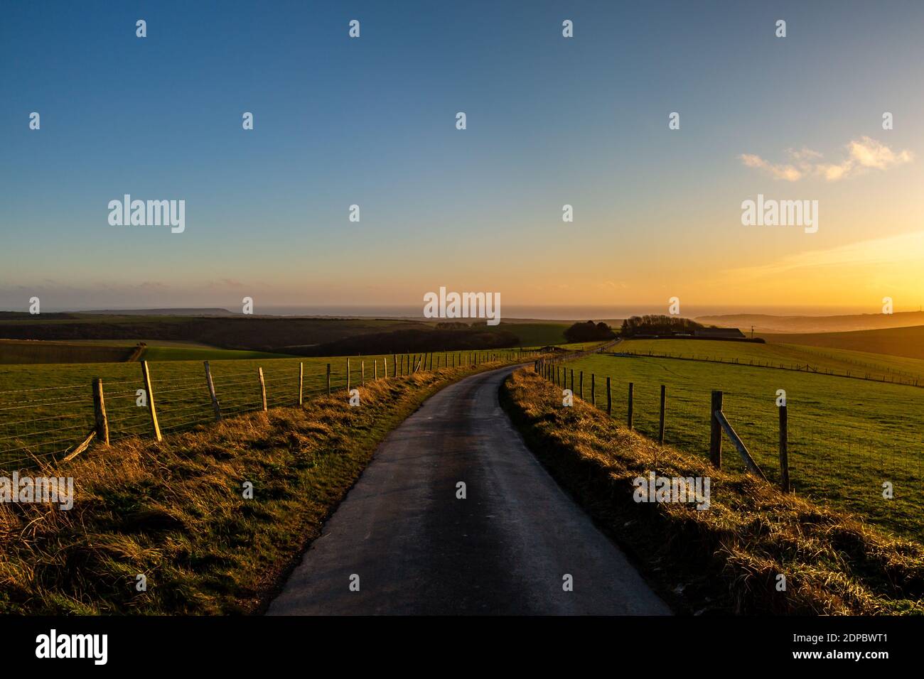 Blick entlang einer Landstraße auf Firle Beacon, mit einem Sonnenuntergang Himmel vor Stockfoto