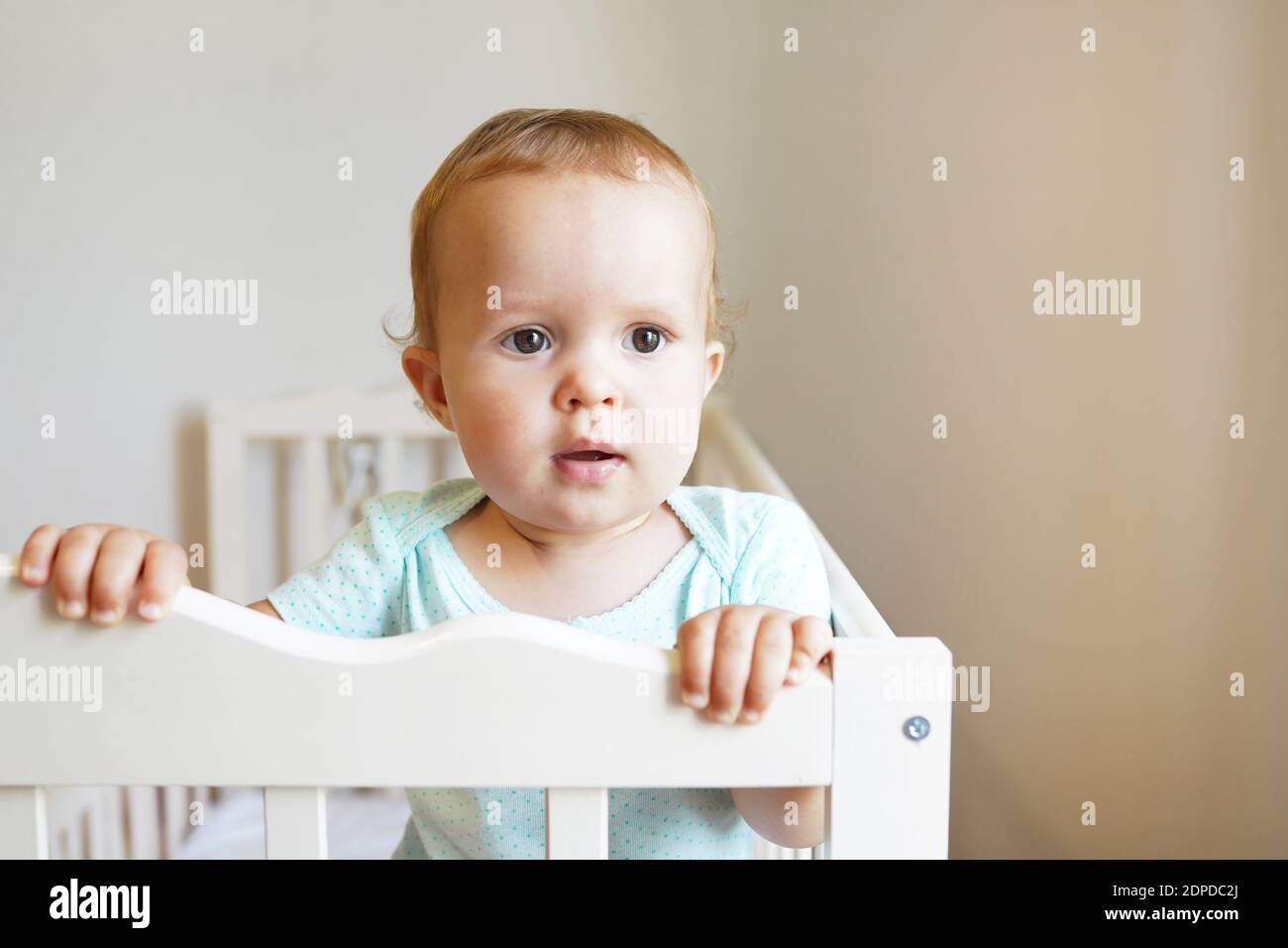 Kleines Kind steht im Kinderbett, schönes Kind mit Blick auf das kleine Bett  Stockfotografie - Alamy