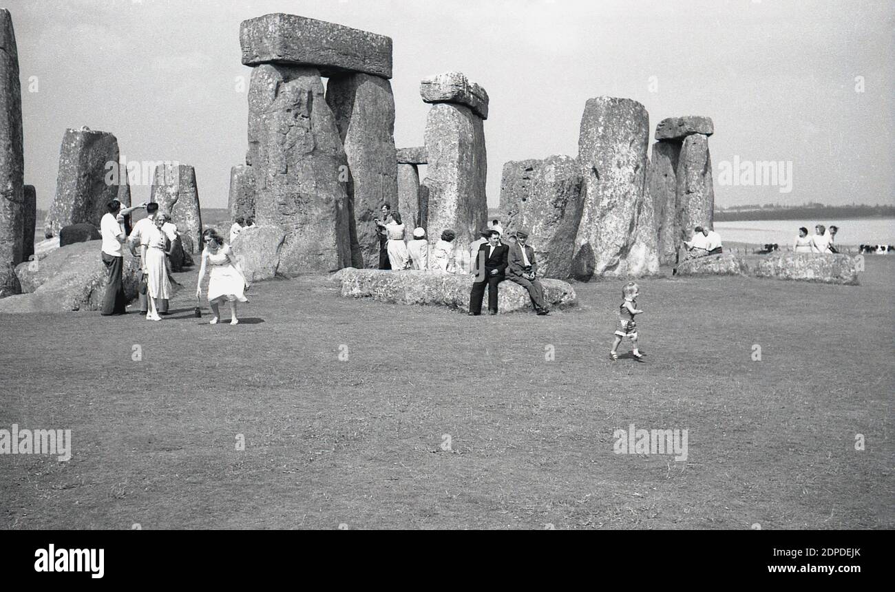 1950er Jahre, historisch, Menschen in Stonehenge, dem berühmten prähistorischen Denkmal in Wiltshire, England, Großbritannien. Zu dieser Zeit, in einer entspannteren Zeit, gingen die Besucher frei zwischen den alten Sarsensteinen und saßen ohne Probleme darauf, was später, wenn der Zutritt zu den Steinen kontrolliert wurde, nicht erlaubt war. Stockfoto