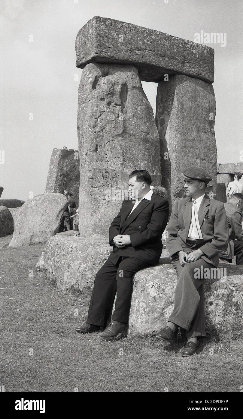 1950er Jahre, historisch, Stonehenge, das berühmte prähistorische Denkmal auf der Salisbury Plain in Wiltshire, England, Großbritannien. Zu dieser Zeit konnten Besucher frei zwischen den alten Sarsensteinen spazieren gehen und darauf sitzen - wie die beiden Männer hier sehen - ohne Probleme, was später nicht erlaubt war. Stockfoto