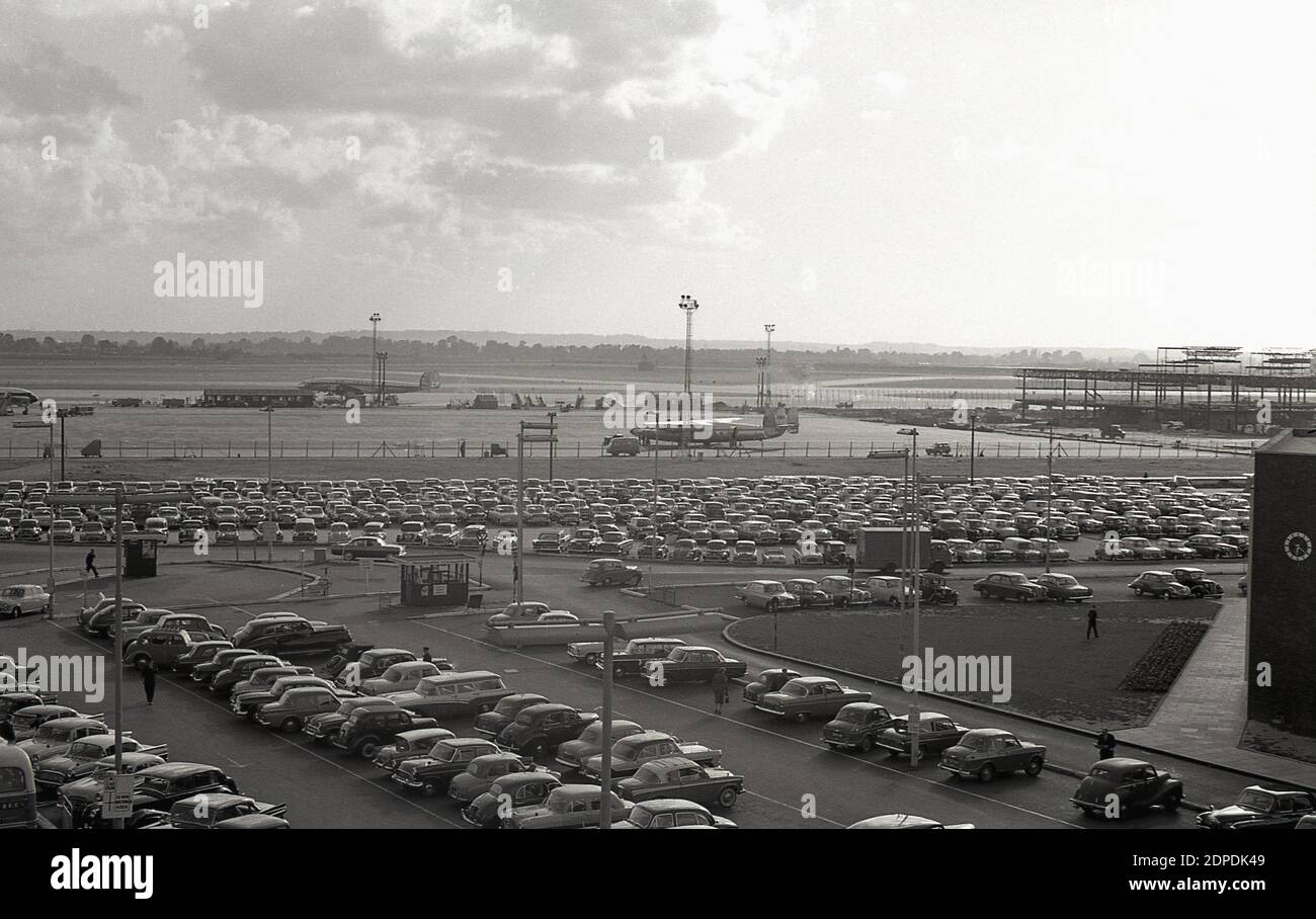Ende der 1950er Jahre, historische Außenansicht der Start- und Landebahn und geparkte Autos am London Airport, später als London Heathrow Airport umgemahmt. Auf der rechten Seite sind Bauarbeiten an einem neuen Terminal zu sehen. Stockfoto