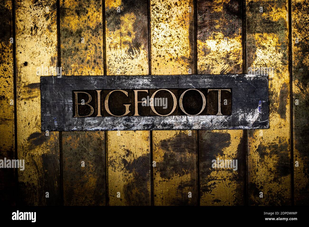 Bigfoot Text auf grunge texturiertem Kupfer und Gold Hintergrund Stockfoto