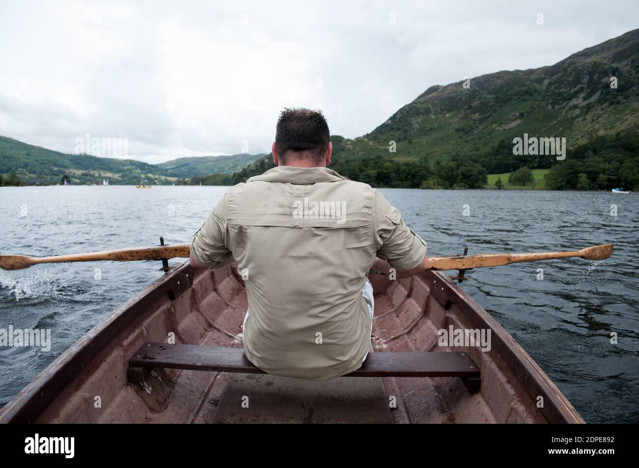 Mann rudert ein kleines Boot über einen See Stockfoto