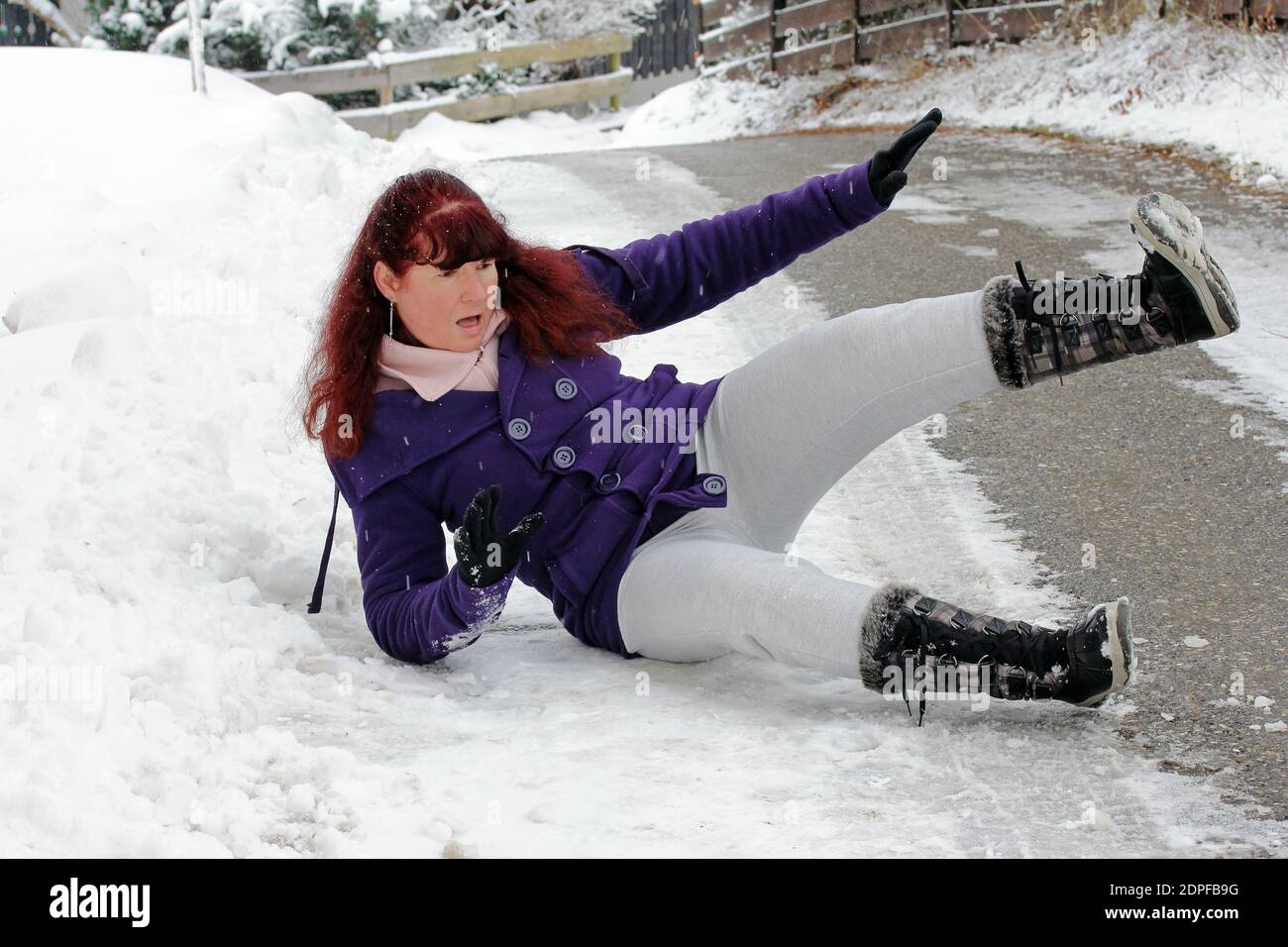 Unfallgefahr im Winter. Eine Frau rutscht auf der glatten Straße aus Stockfoto