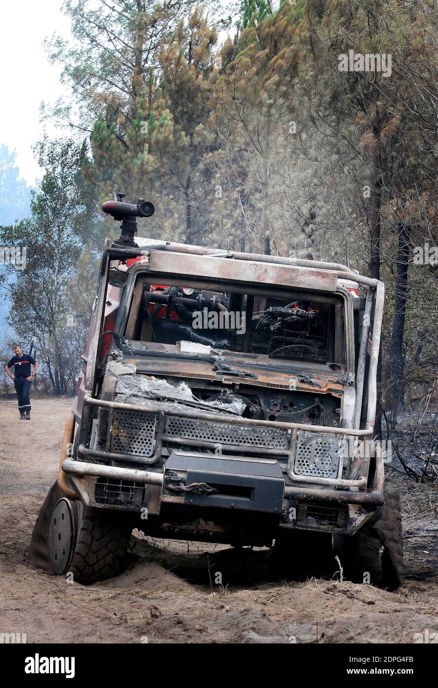 Ein Feuerwehrmann sieht zwei Feuerwehrautos, die am 27. Juli 2015 in einem Kiefernwald von Saint-Jean d'Illac in der Nähe von Bordeaux, Frankreich, durch einen Brand zerstört wurden, vier Tage nach einem Waldbrand, der mehr als 500 Hektar zerstört und die Evakuierung von 270 Häusern in der Gegend erzwungen hat. Mehr als 700 Einsatzkräfte haben es geschafft, den Brand, gegen den sie seit Juli 24 kämpfen, einzudämmen. Foto von Patrick Bernard/ABACAPRESS.COM Stockfoto