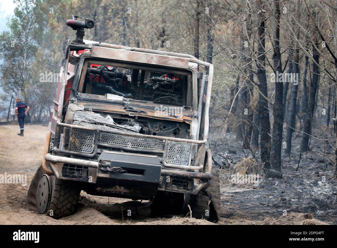 Ein Feuerwehrmann sieht zwei Feuerwehrautos, die am 27. Juli 2015 in einem Kiefernwald von Saint-Jean d'Illac in der Nähe von Bordeaux, Frankreich, durch einen Brand zerstört wurden, vier Tage nach einem Waldbrand, der mehr als 500 Hektar zerstört und die Evakuierung von 270 Häusern in der Gegend erzwungen hat. Mehr als 700 Einsatzkräfte haben es geschafft, den Brand, gegen den sie seit Juli 24 kämpfen, einzudämmen. Foto von Patrick Bernard/ABACAPRESS.COM Stockfoto