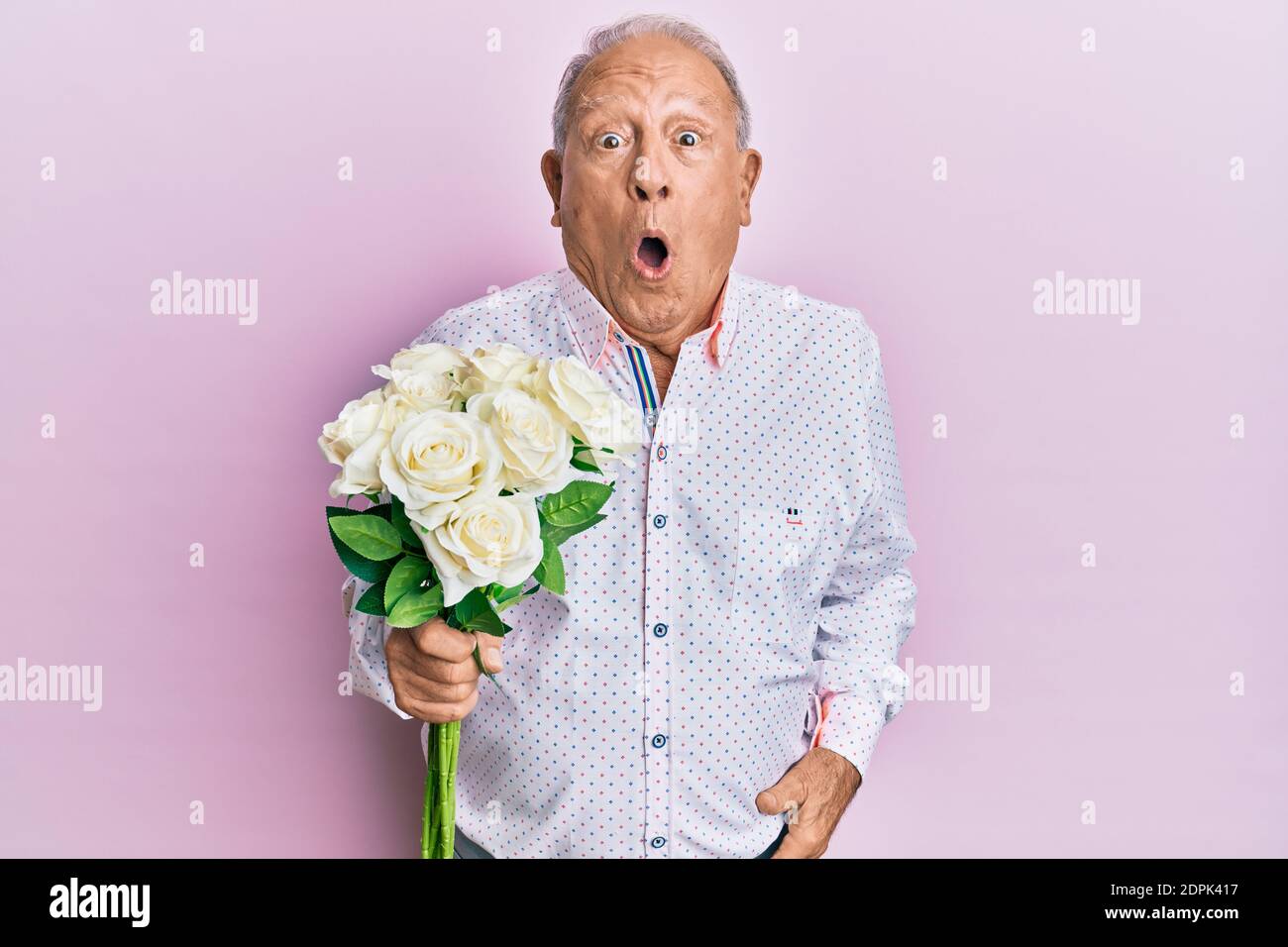 Älterer kaukasischer Mann, der Blumen hielt, erschrocken und erstaunt mit offenem Mund für ein Überraschungs-, Unglauben-Gesicht Stockfoto
