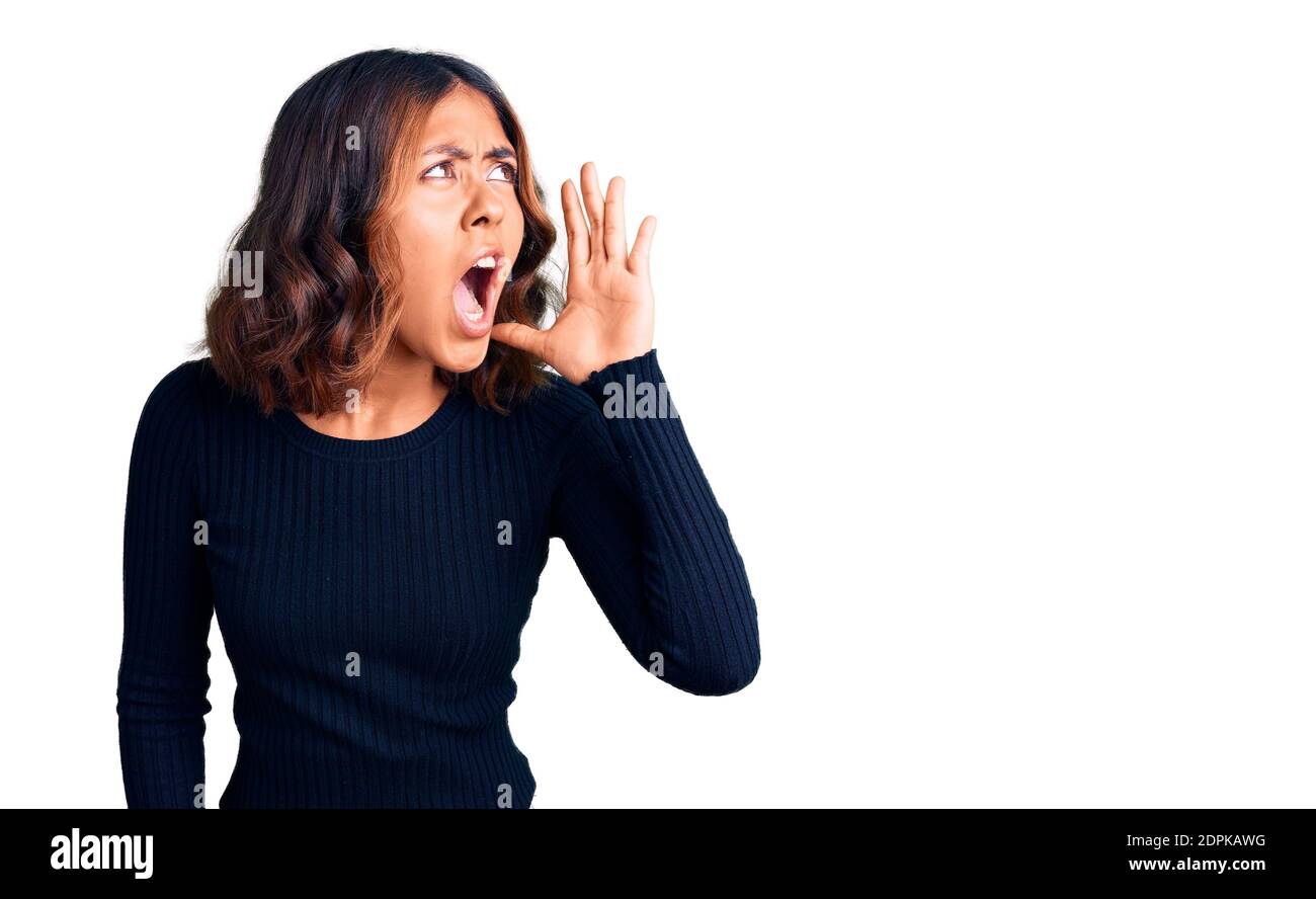 Junge schöne gemischte Rasse Frau tragen lässige Kleidung schreien und schreien laut zur Seite mit Hand auf Mund. Kommunikationskonzept. Stockfoto