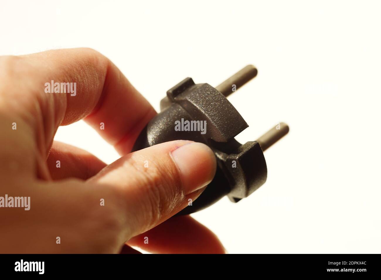 Finger halten den Netzstecker auf weißem Hintergrund Stockfoto