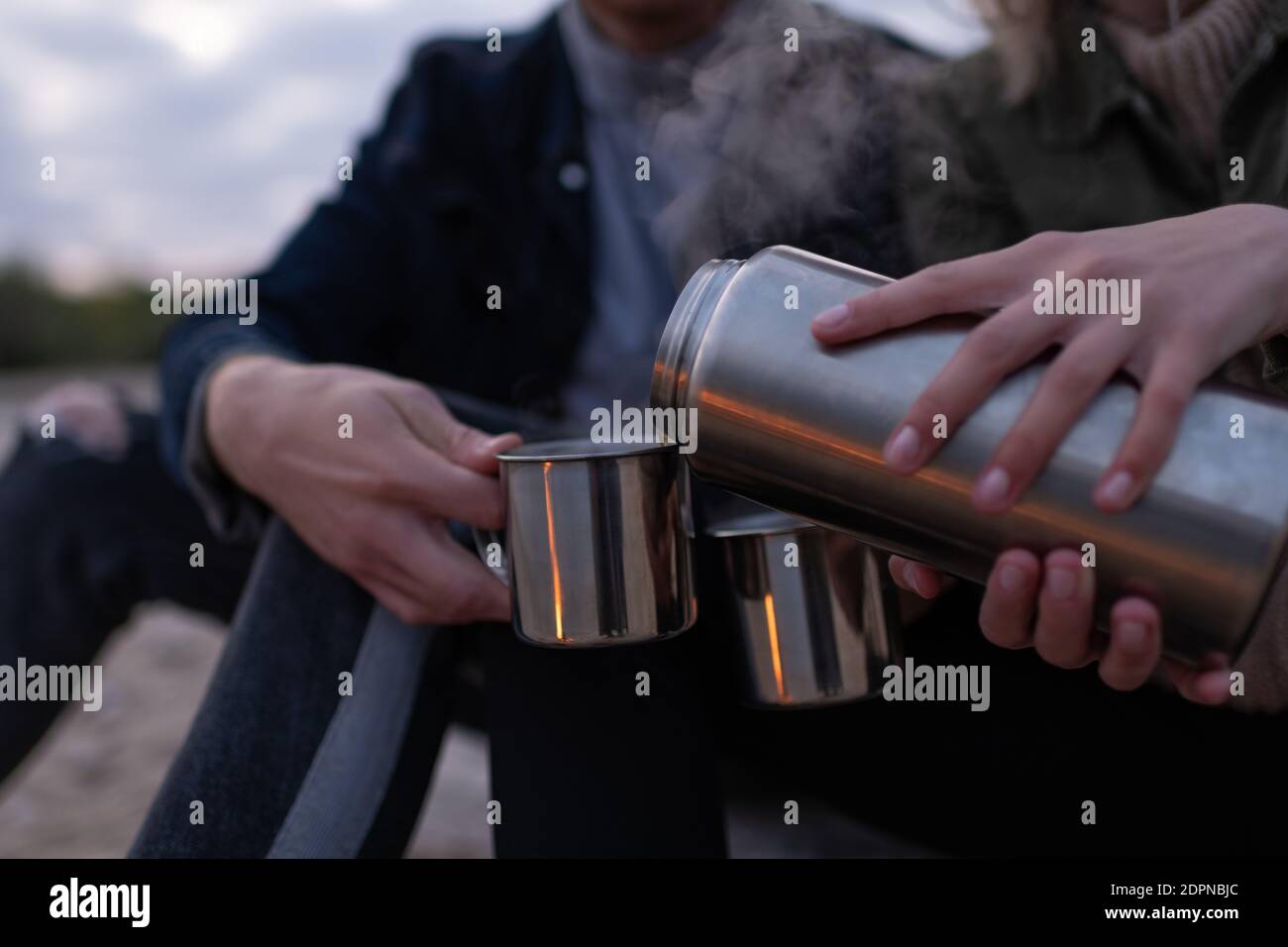 Nahaufnahme anonyme weibliche Füllung Tassen mit frischem heißen Tee für Freund beim Entspannen in der Natur am Abend Stockfoto