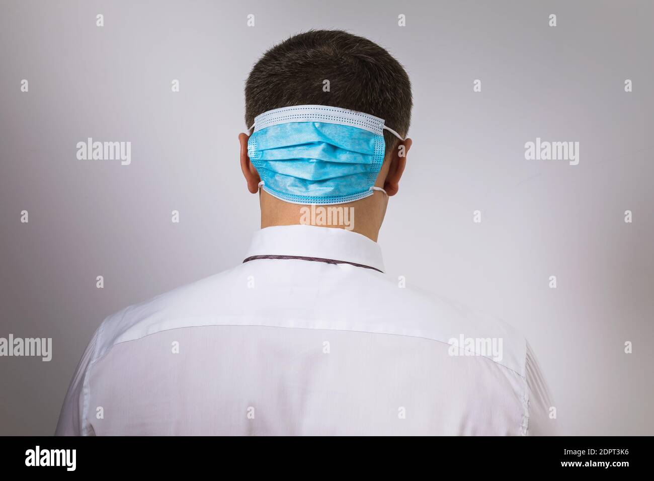 Ein Mann mit einer medizinischen Maske auf dem Hinterkopf. Konzept zum Thema Depression aufgrund der Quarantäne durch das Coronavirus. Stockfoto