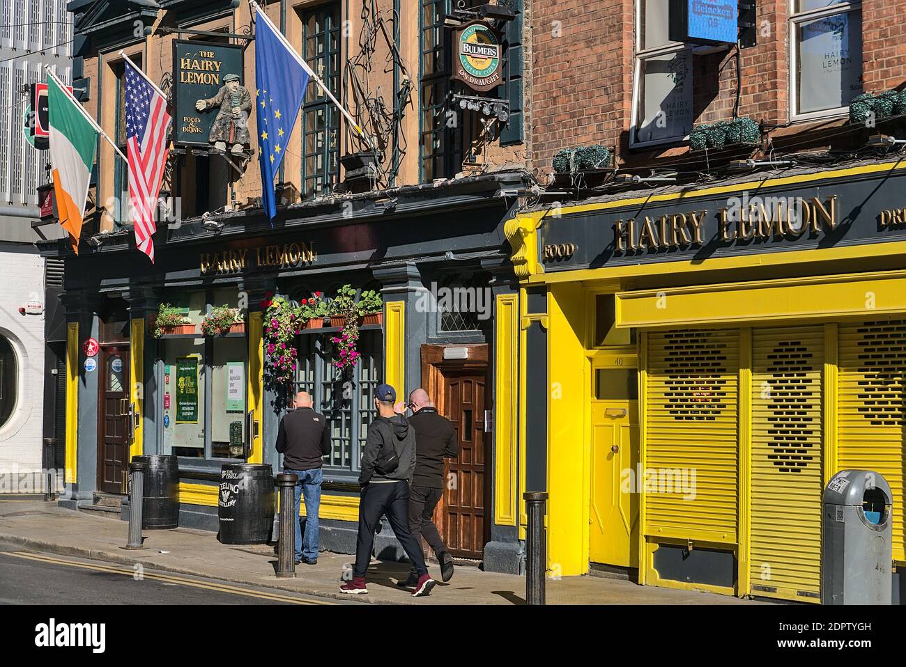 Dublin, Irland - 27. September 2020: Zufällige Leute, die an einem sonnigen Tag auf der Straße durch den Hairy Lemon Food and Drink Pub gehen. EU, USA und irische Flagge Stockfoto