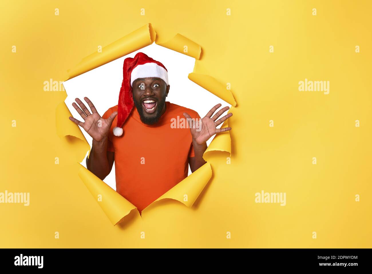 Afro Mann mit Hut ist glücklich, weil Weihnachten ist. Gelber Hintergrund Stockfoto