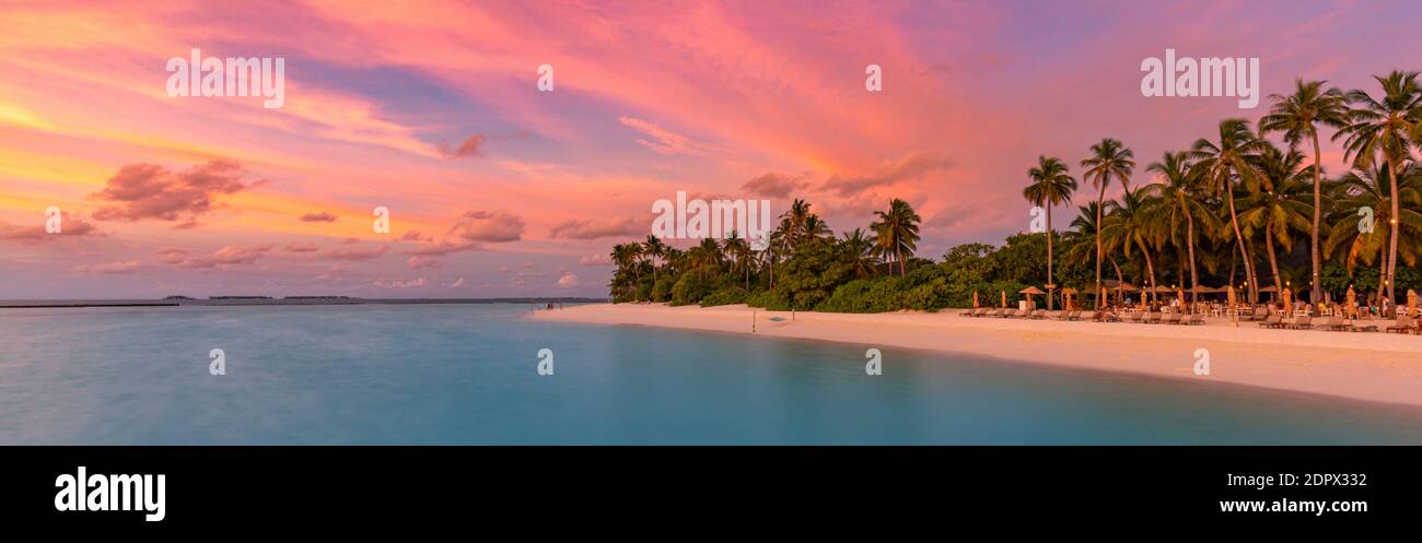 Tropisches Strandpanorama Sonnenuntergang Sommerhimmel. Panorama-Strandlandschaft. Strand und Seestrand des Resorts. Orangefarbener und goldener Sonnenuntergang, weiche Sandpalmen Stockfoto
