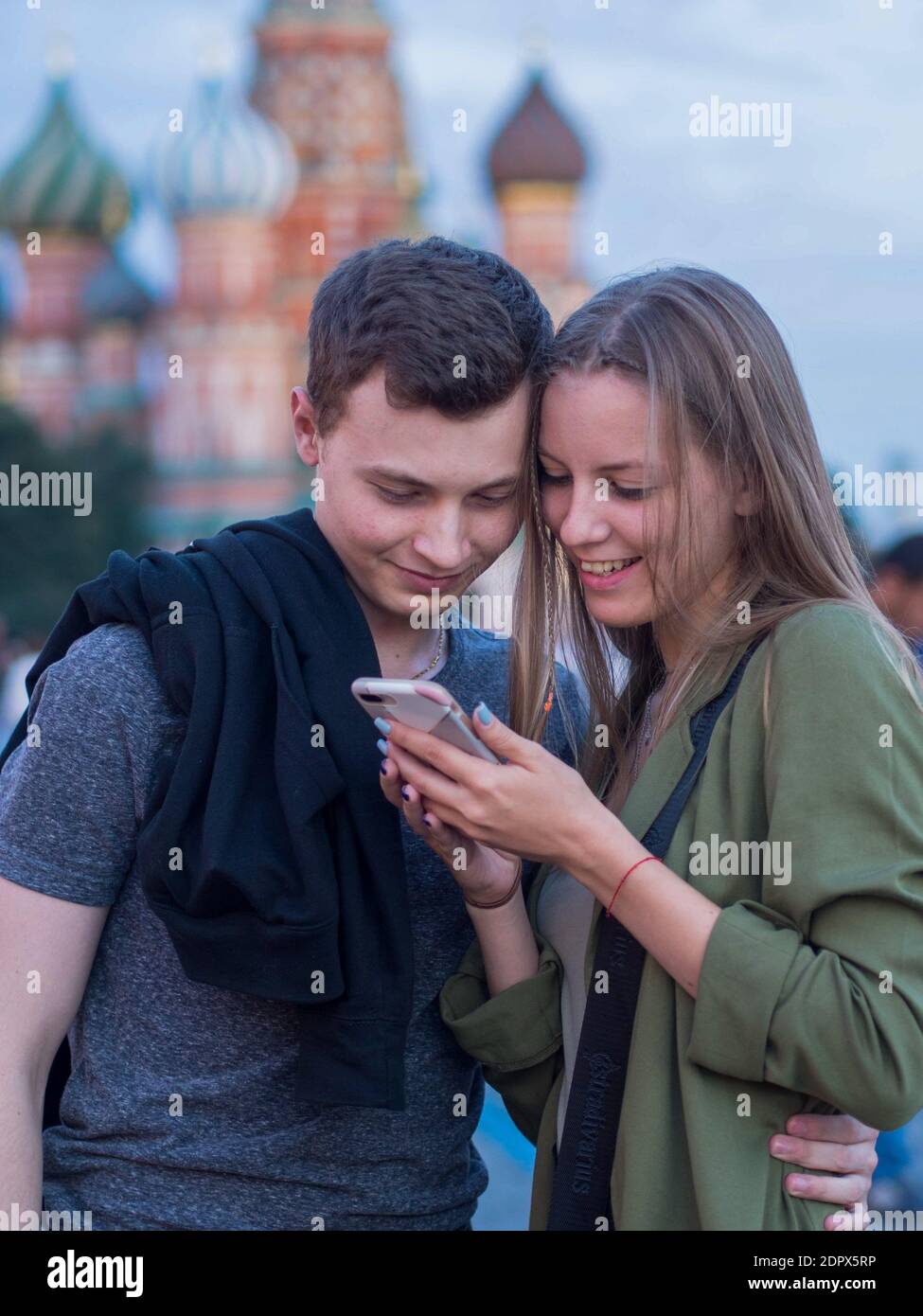 Ein Paar wirft einen genaueren Blick auf etwas auf einem Smartphone auf Red Square. Stockfoto