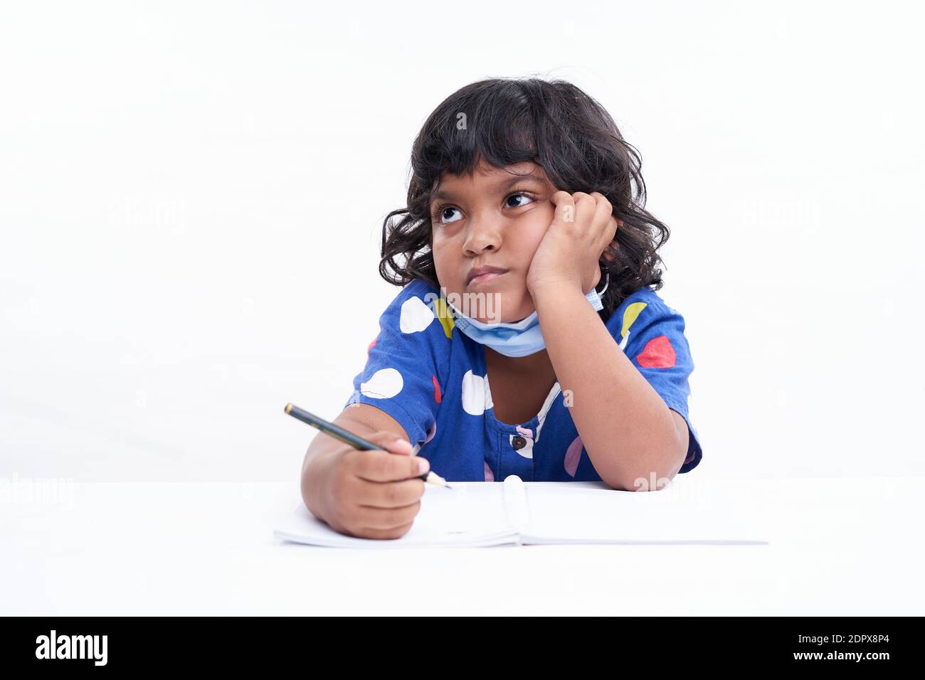 Kleine Schulmädchen sitzt an EINEM Schreibtisch und arbeitet an ihrer Hausarbeit, Home Bildung Konzept Stockfoto