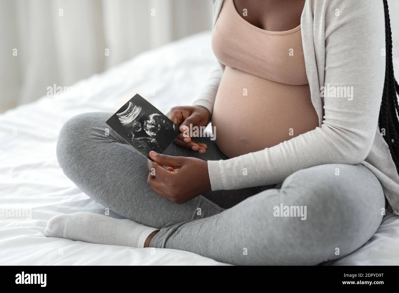 Fetale Entwicklung. Schwangere afrikanische Frau, die Baby-Ultraschall-Scan zu Hause Stockfoto