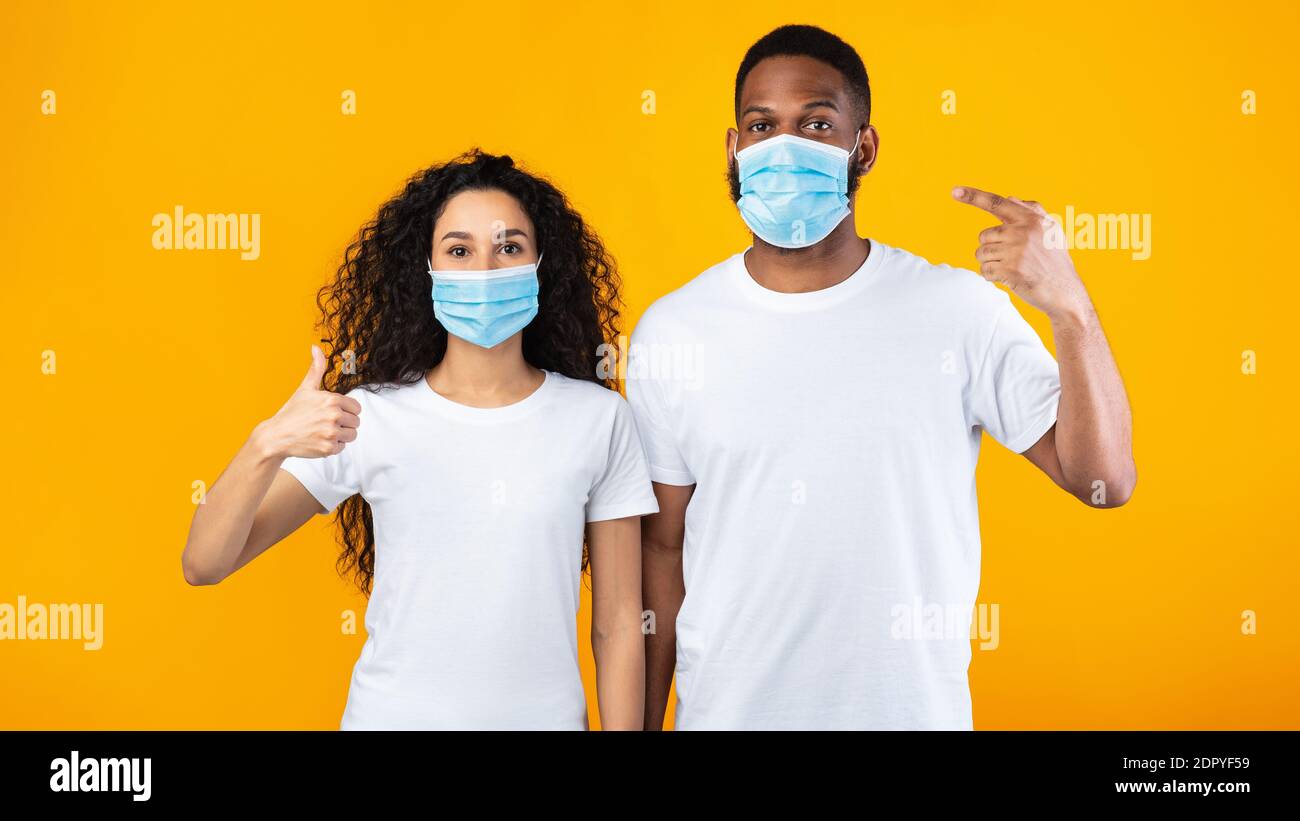 Paar Tragen Gesicht Masken Gestikulierenden Daumen-Up Stehen Über Gelben Hintergrund Stockfoto