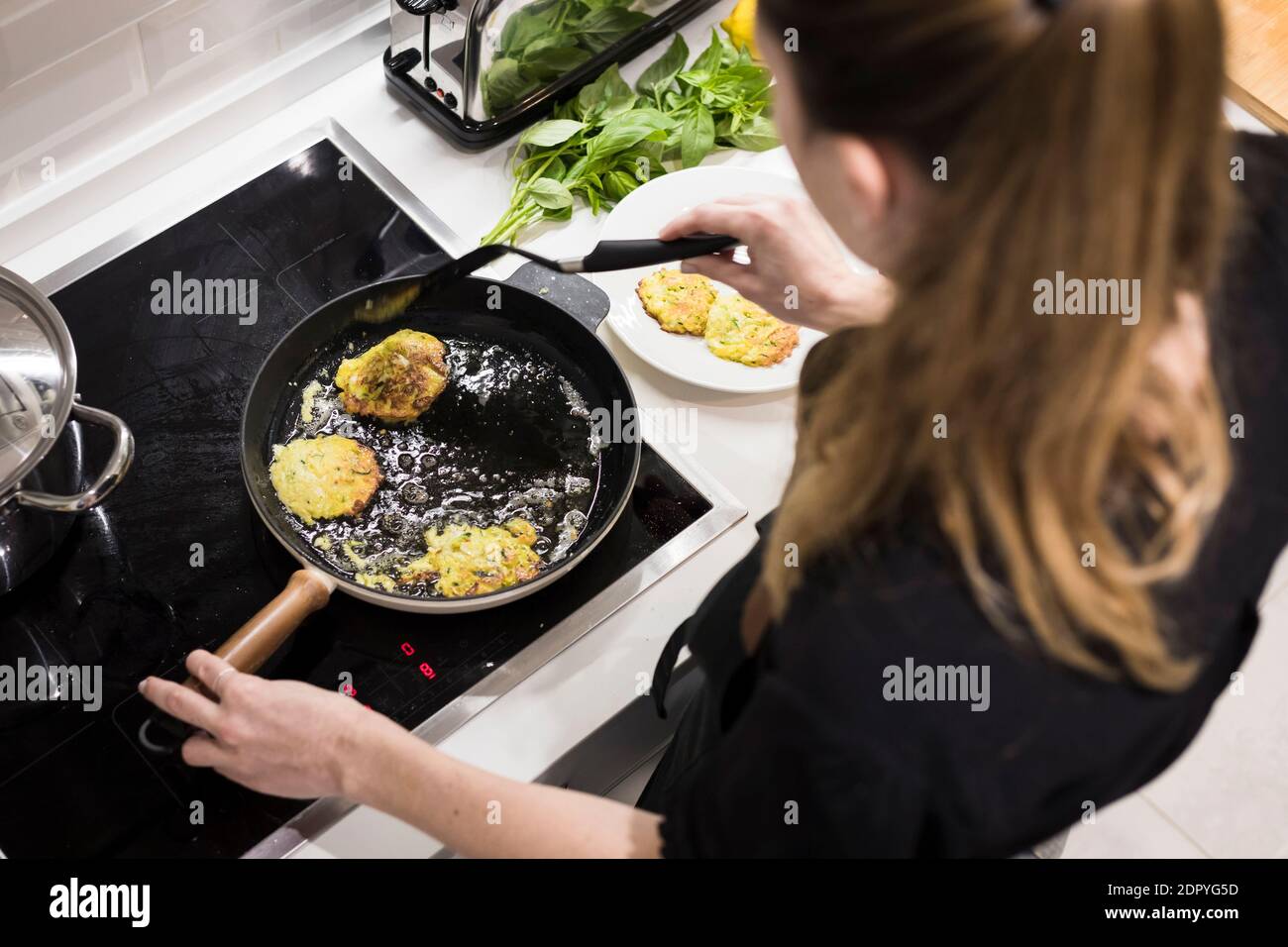Junge charmante schwedische Frau, die zu Hause in ihrer Küche kocht und gesundes mediterranes Essen für ihre Familie zubereitet. Junge Lebensmittel-Blogger tun Essen vorbereiten Stockfoto