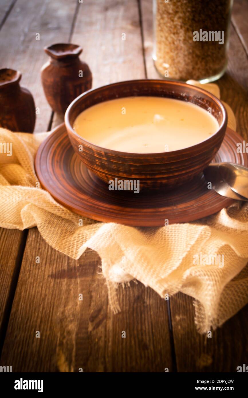 Suppe aus Buchweizen mit Milch in einer Keramikschale auf rustikalem Tisch, vertikales Bild Stockfoto