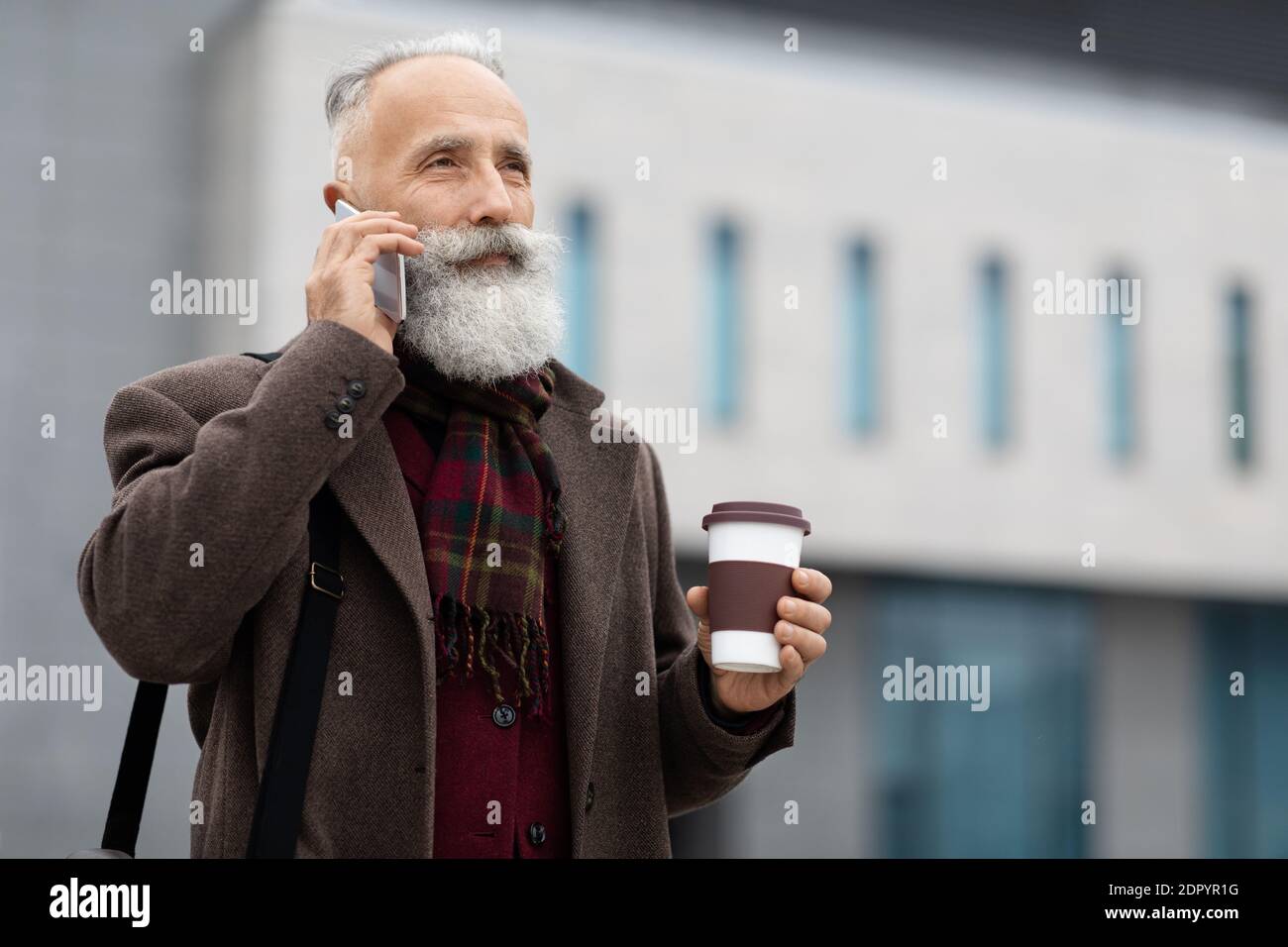 Wohlhabender älterer Mann mit Kaffee zu gehen, um Geschäftsanruf Stockfoto