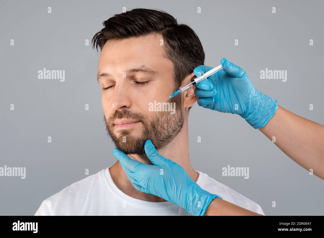 Attraktiver Mann mittleren Alters immer Anti-Aging-Verfahren, grauer Hintergrund Stockfoto