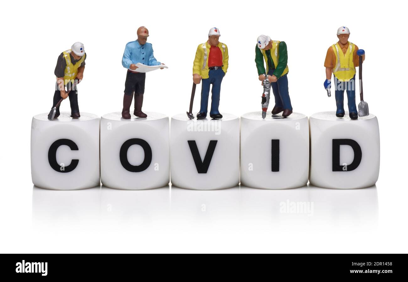 Miniatur-Bauarbeiter auf Kunststoff-Würfel Rechtschreibung des Wortes COVID Stockfoto