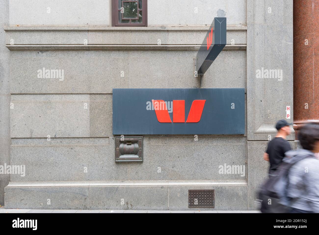 Ein Westpac Bank-Symbol auf Fußweghöhe mit verschwommenen Menschen, die an einer Bank in Sydney in Australien vorbeigehen Stockfoto