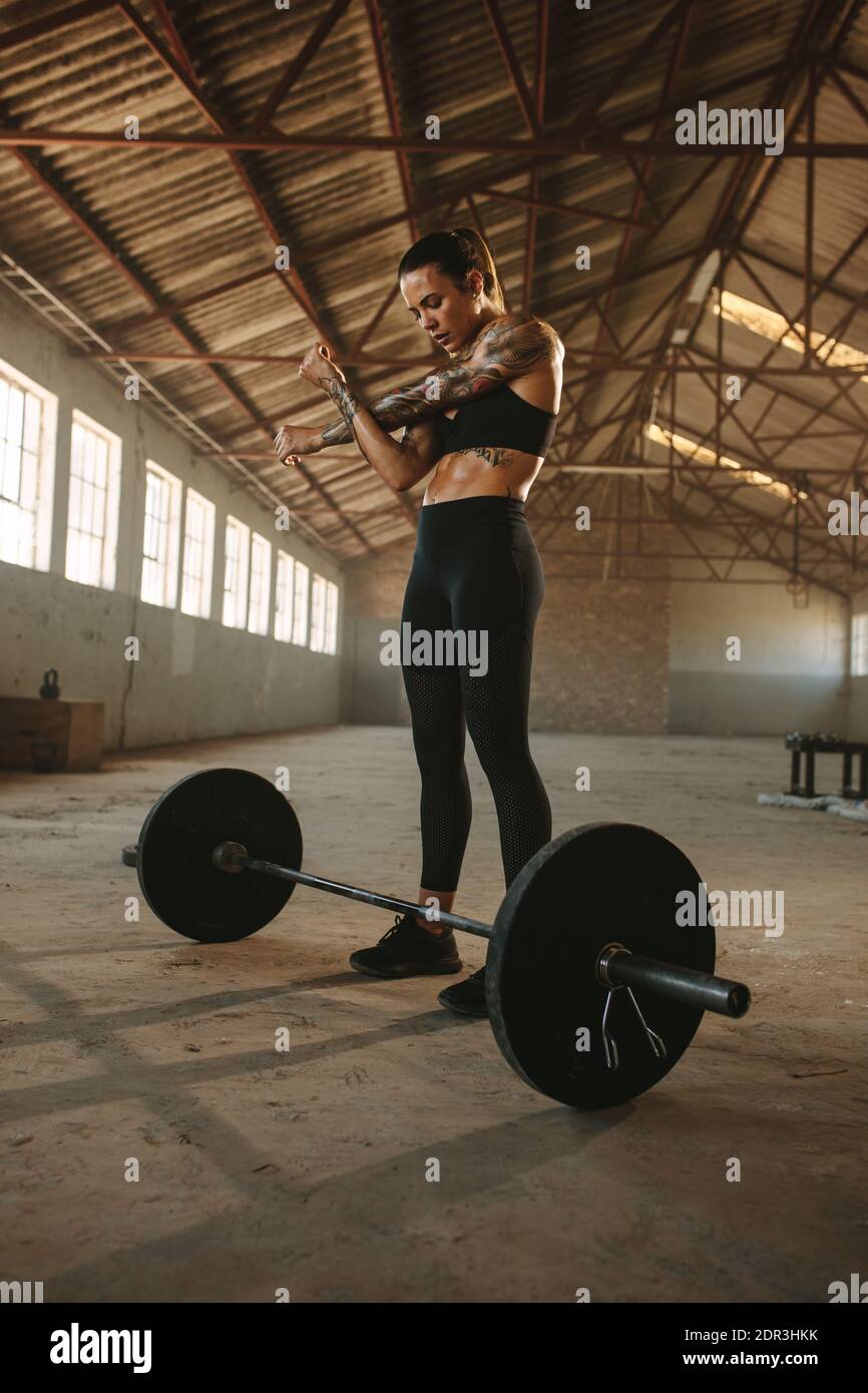 Frau, die die Arme vor dem Gewichtheben streckt und im Fitnessbereich in der alten Fabrik arbeitet. Frau Stockfoto