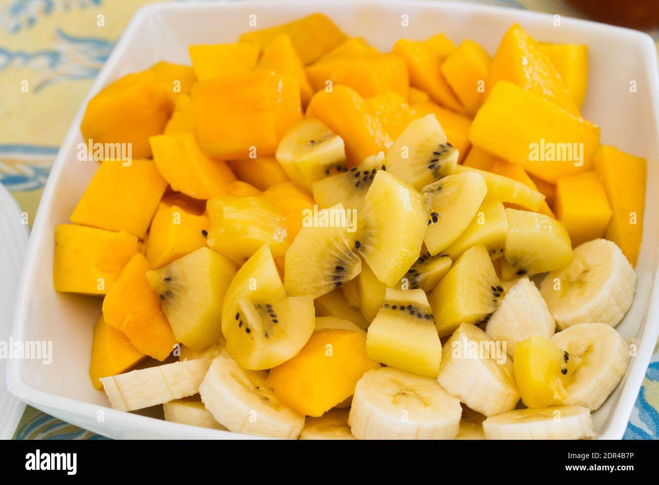 Große Platte mit frischen exotischen Früchten zum Frühstück, Mango, Bananen, goldenen Kiwi auf einem Tisch Stockfoto
