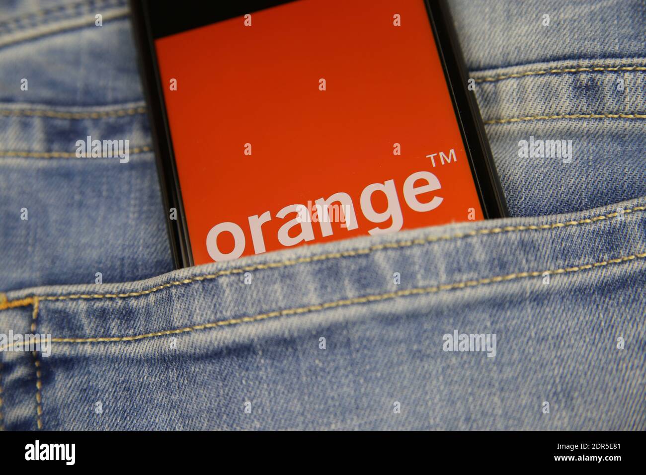 Viersen, Deutschland - 9. Mai. 2020: Nahaufnahme des Smartphone-Bildschirms in blauer Jeanstasche mit Logo-Schriftzug des französischen Mobilfunkanbieters Orange S. A. (s Stockfoto