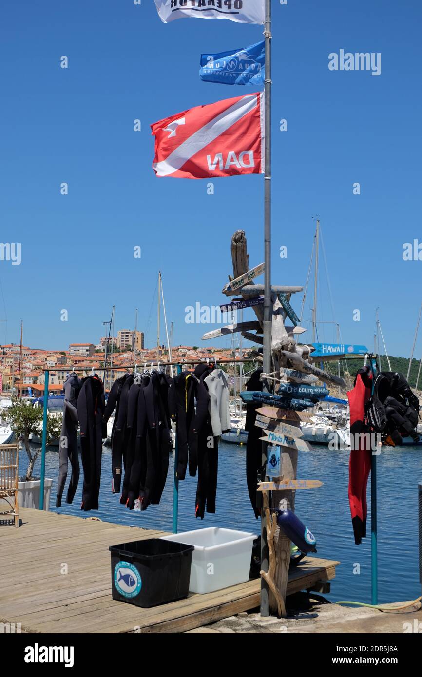 Tauchschule zeigt Neoprenanzüge neben Treibholzschildern, die Ablenkungen von weit entfernten Orten zeigen. Stockfoto
