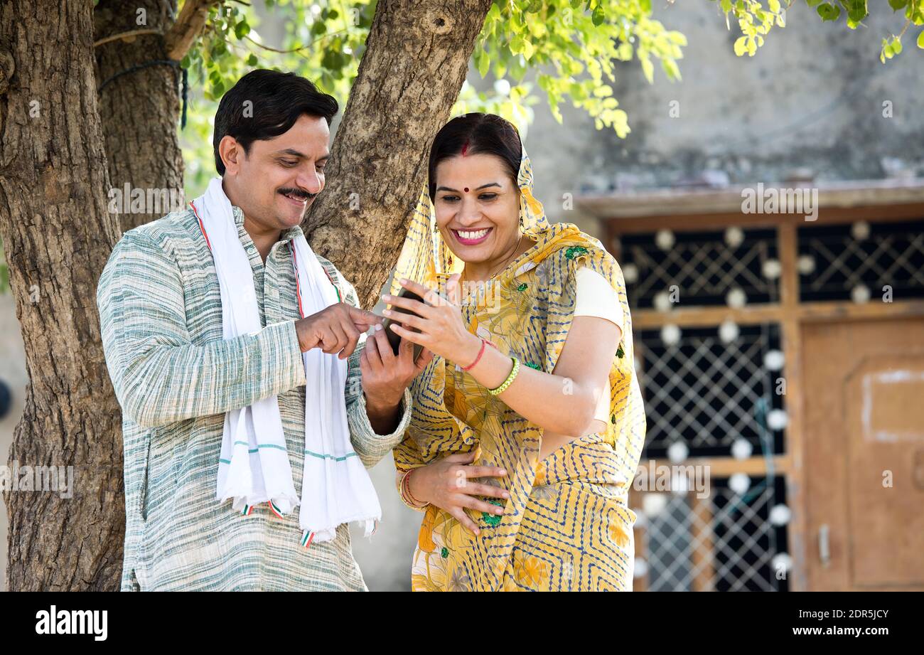 Ländliche indische Frau, die ihren Mann auf dem Handy mit SMS ansieht Telefon im Dorf Stockfoto