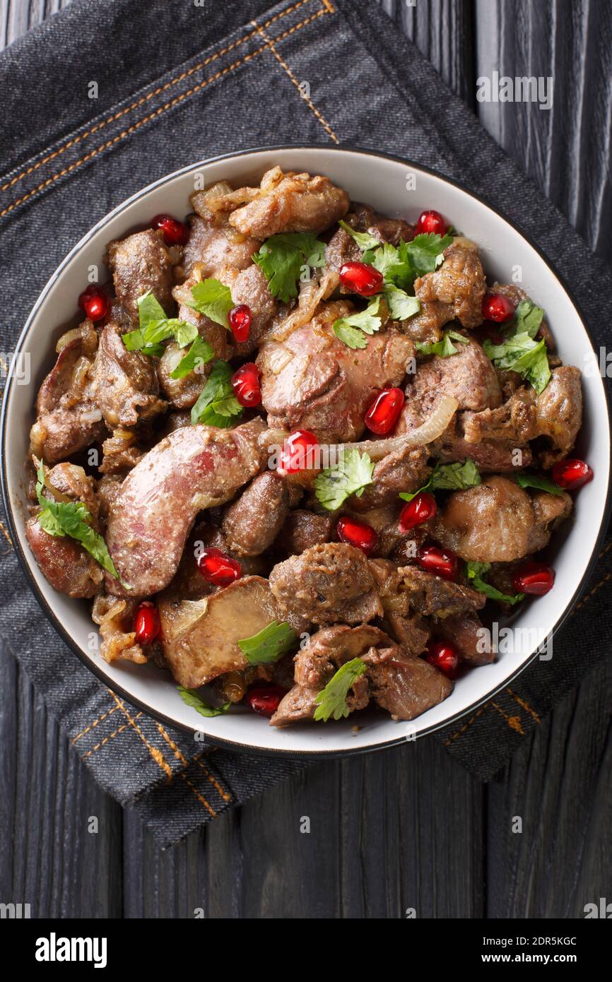 Kuchmachi georgischen Gericht aus Innereien mit Gewürzen, Zwiebeln und Granatapfel Nahaufnahme in einer Schüssel auf dem Tisch. Vertikale Draufsicht von oben Stockfoto