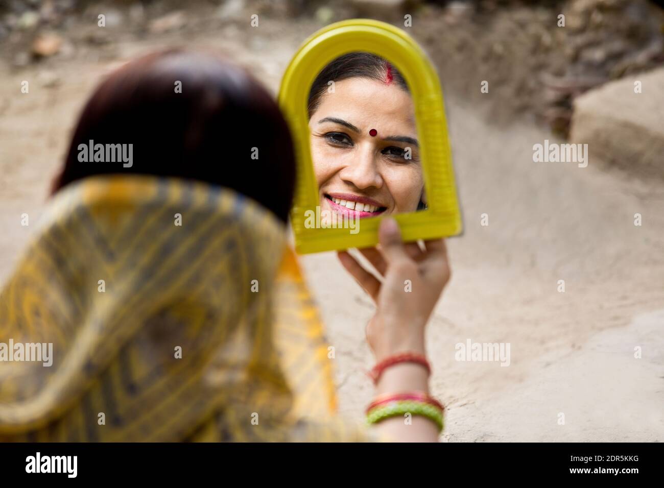 Ländliche Frau, die vor ihrem Haus in den Spiegel schaut Stockfoto
