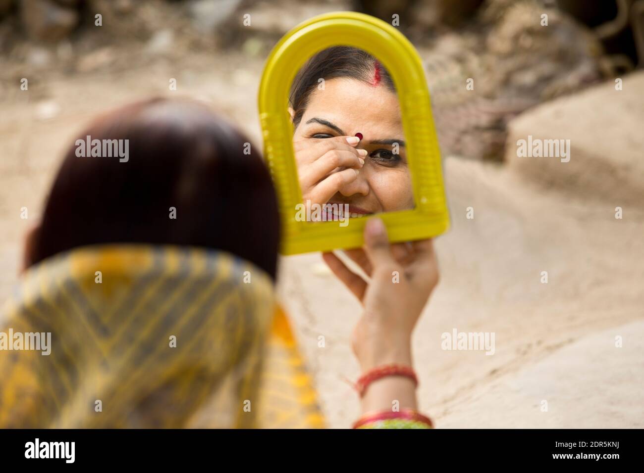 Ländliche Frau, die vor ihrem Haus in den Spiegel schaut Stockfoto