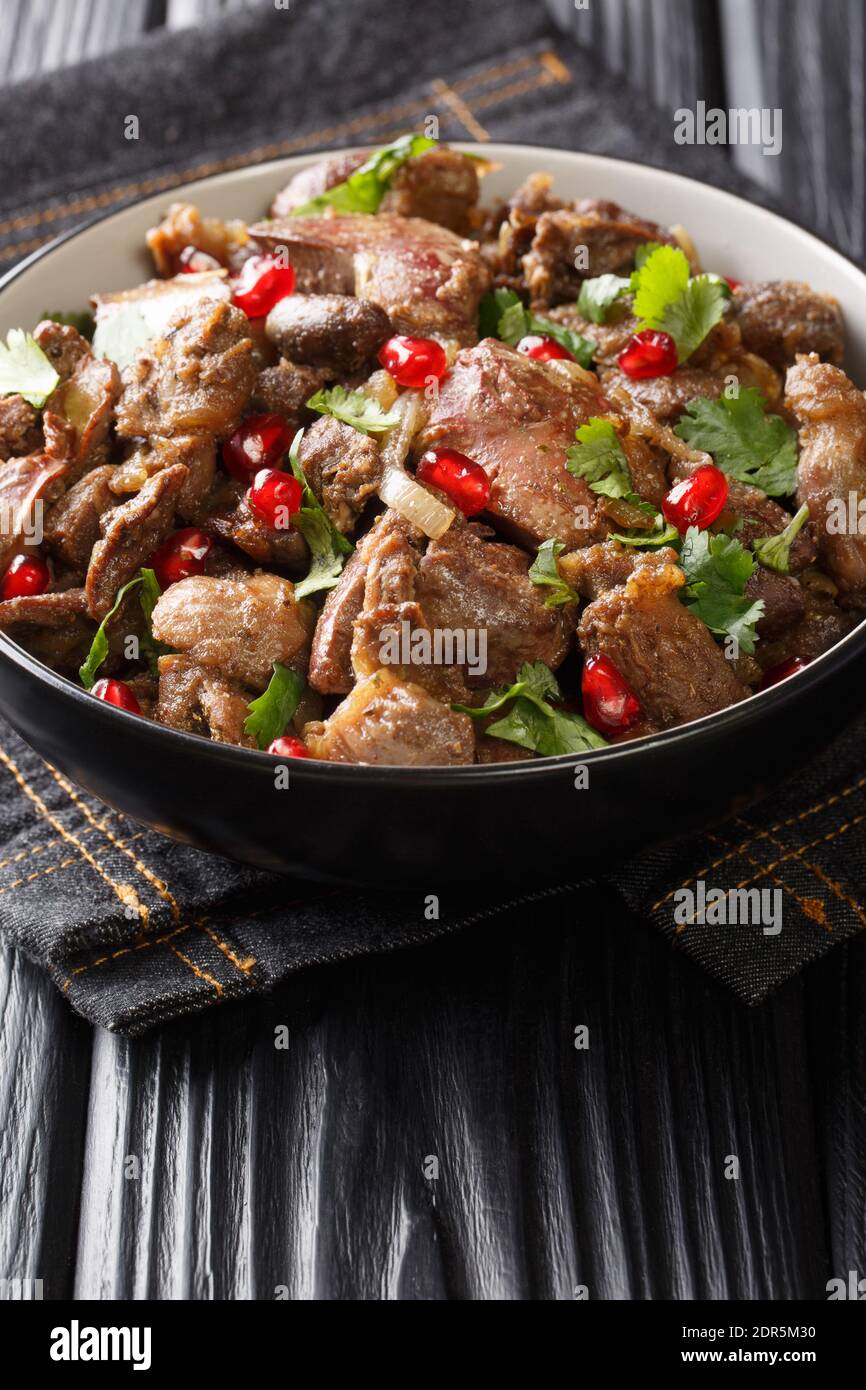 Köstliche Kuchmachi aus Hühnerfleisch mit Gewürzen, Zwiebeln und Granatapfel close-up in einer Schüssel auf dem Tisch. Vertikal Stockfoto