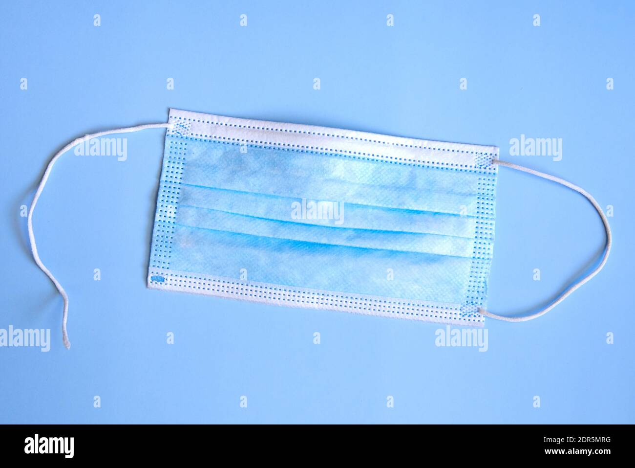 Zerrissene medizinische Maske auf blauem Hintergrund, das Konzept der Viruserkrankungen, Coronavirus. Stockfoto