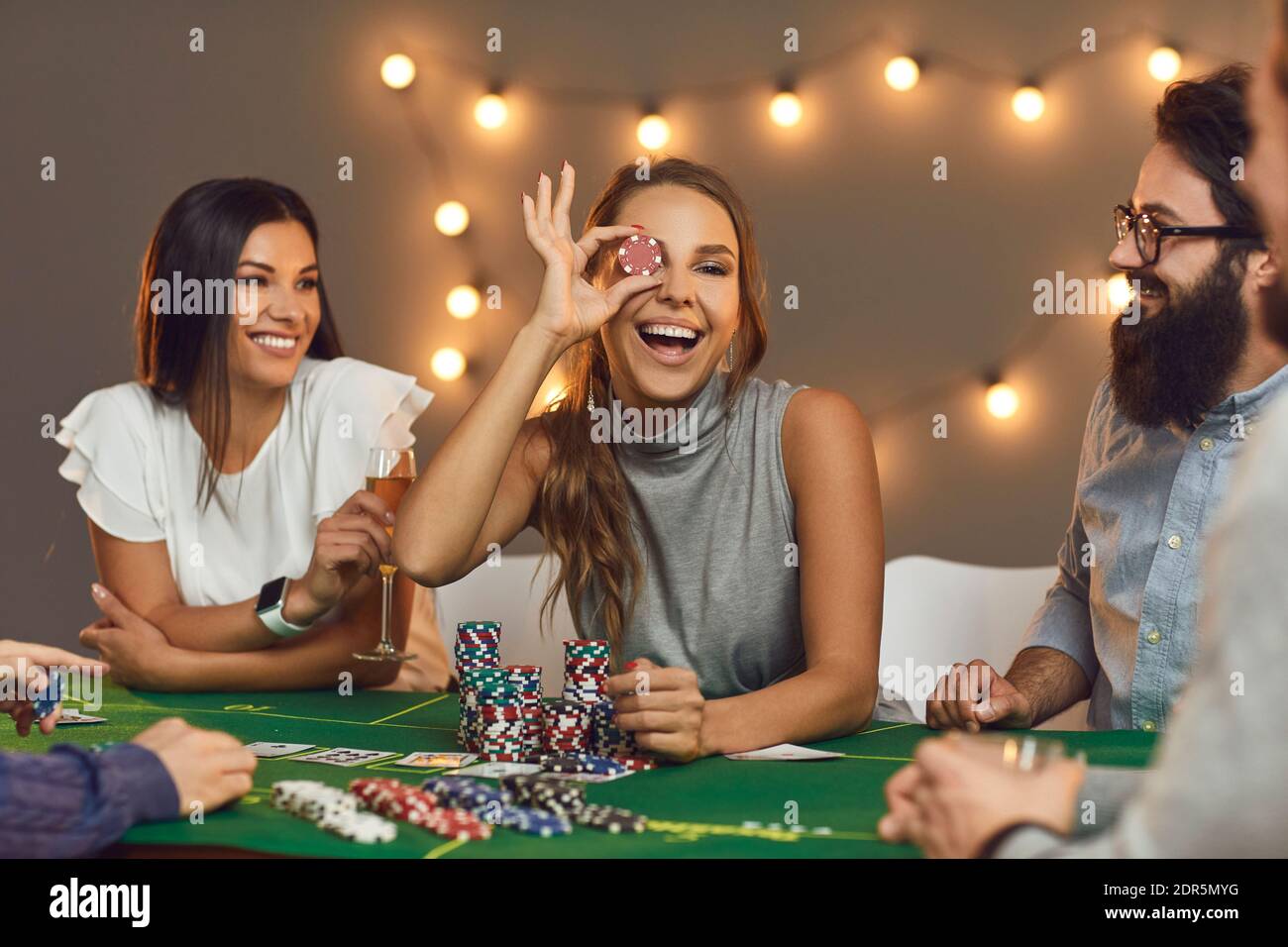 Gruppe lächelnder Freunde, die Brettspiele mit Chips spielen Zu Hause Stockfoto