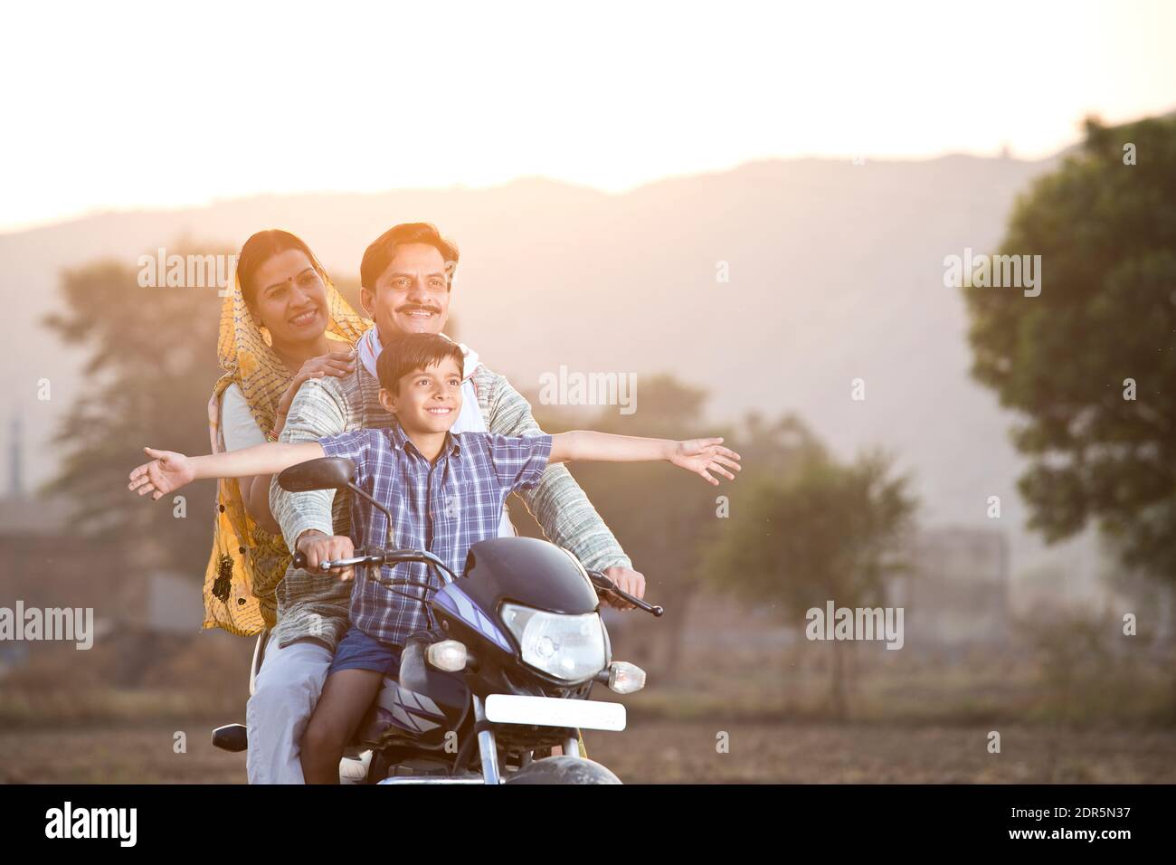 Glückliche ländliche indische Familie Reiten auf Motorrad Stockfoto