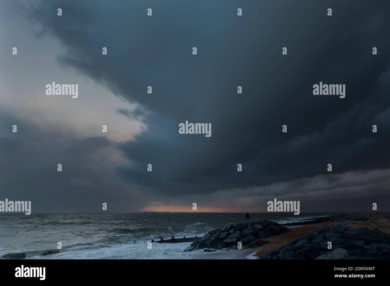 Sturmwolken sammeln sich an der Südküste Englands. Das raue Wetter nähert sich der Küste vom englischen Kanal. Einzelfigur mit Blick auf das Meer. Stockfoto